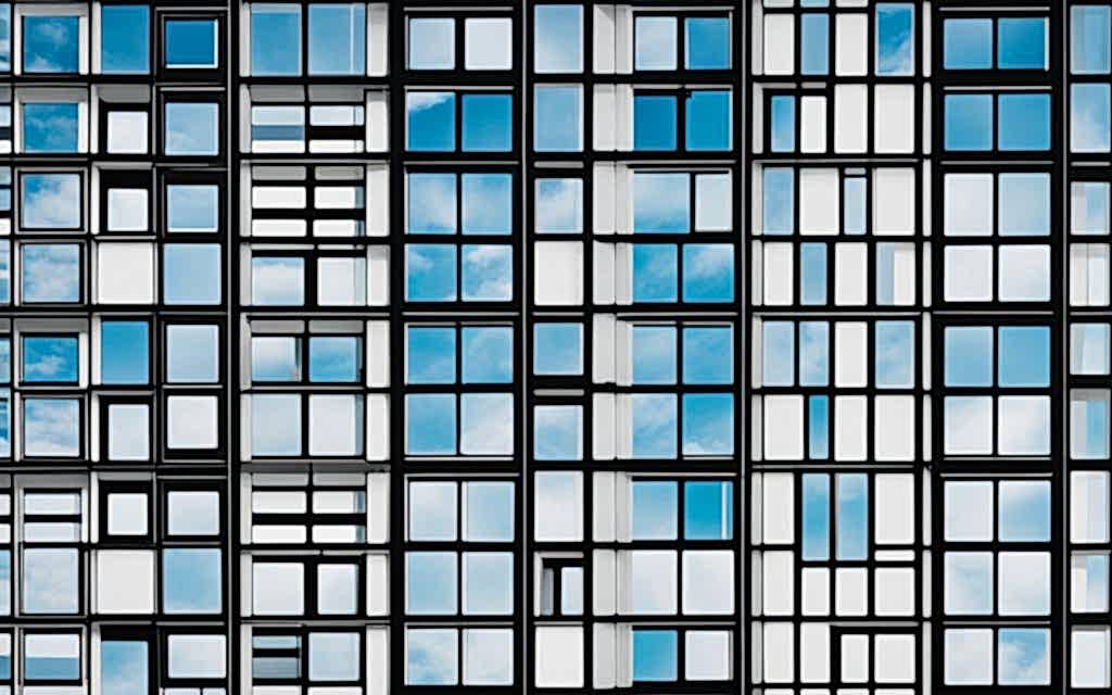 Edificios con mucha ventana de alta eficiencia energética que reflejan las nubes del cielo